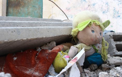 A child's doll sits among building rubble
