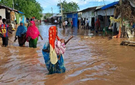 A mother with her baby stand in flood water in Kelafo, Ethiopia during flooding in the Horn of Africa